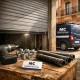 Escena de reparación de puertas de garaje en Barcelona, herramientas en un crate, puerta a medio levantar, luz cálida. Cuales son las mejores empresas de reparacion de puertas de garaje en Barcelona.